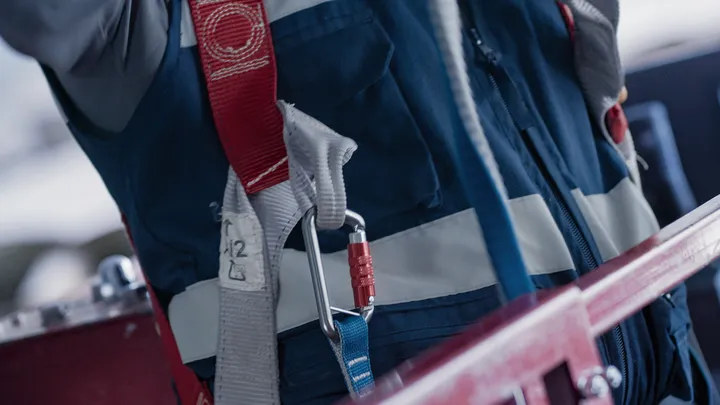 Person wearing safety equipment secured with a harness and carabiner.