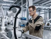 Worker wearing safety equipment uses cordless drill on an industrial robotic arm.