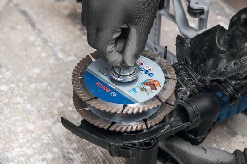 A person wearing safety equipment installs a cutting disc on a wall chaser.