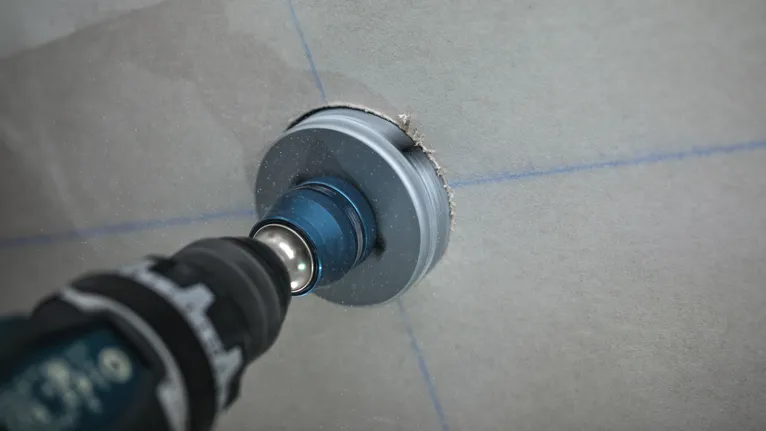 Hole saw drilling a circular opening into a plasterboard wall.