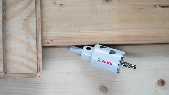 Hole saw drilling into a wooden board.