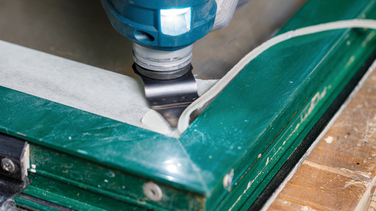 Oscillating tool removing sealant from a window frame.
