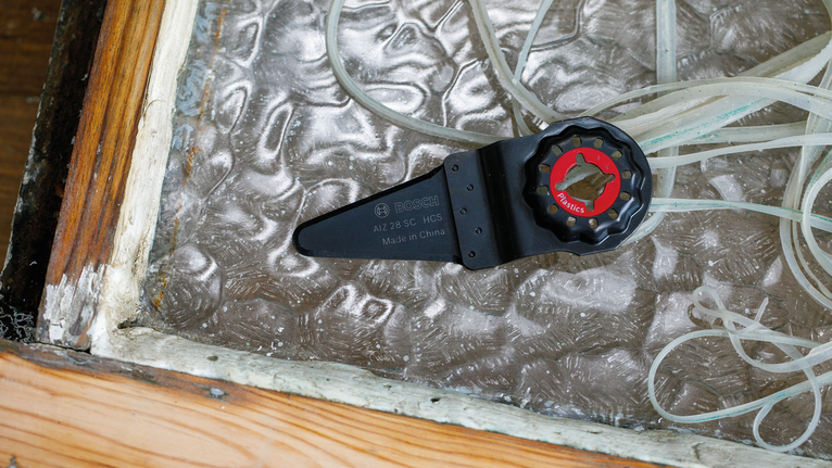 Oscillating tool blade placed next to strips of worn window sealant.