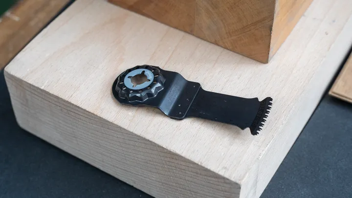 Oscillating multi-tool blade attachment resting on stacked wooden blocks.
