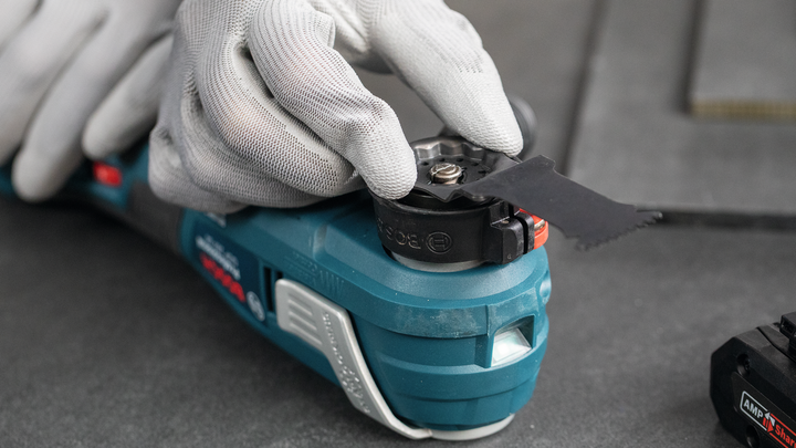 Person wearing safety equipment adjusts a multi-tool blade.