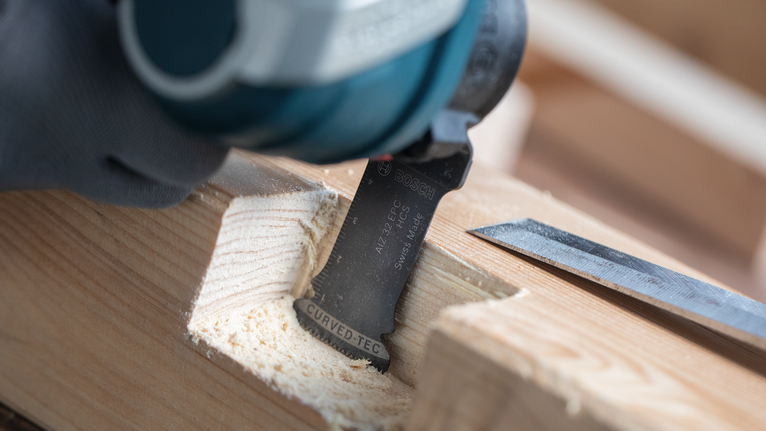 Person wearing safety equipment cutting a groove into wood with a power tool.