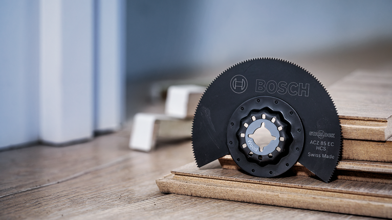 Segment saw blade resting on stacked wooden planks for flooring installation.