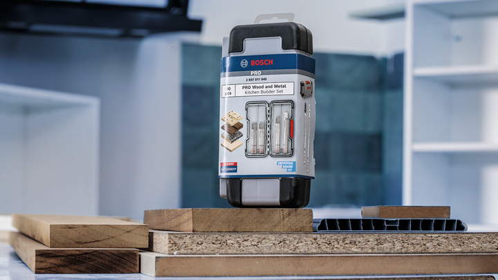 Drill bit set displayed on a table with stacked wood and plastic panels.