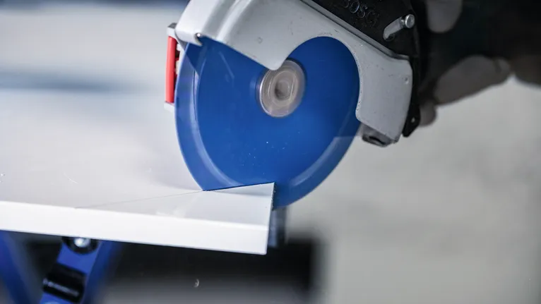 Circular saw cutting a white tile sheet.