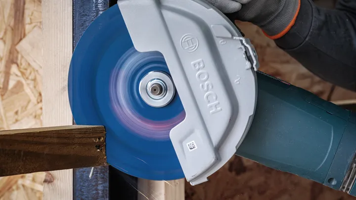 A person wearing safety equipment cuts wood with a circular saw.