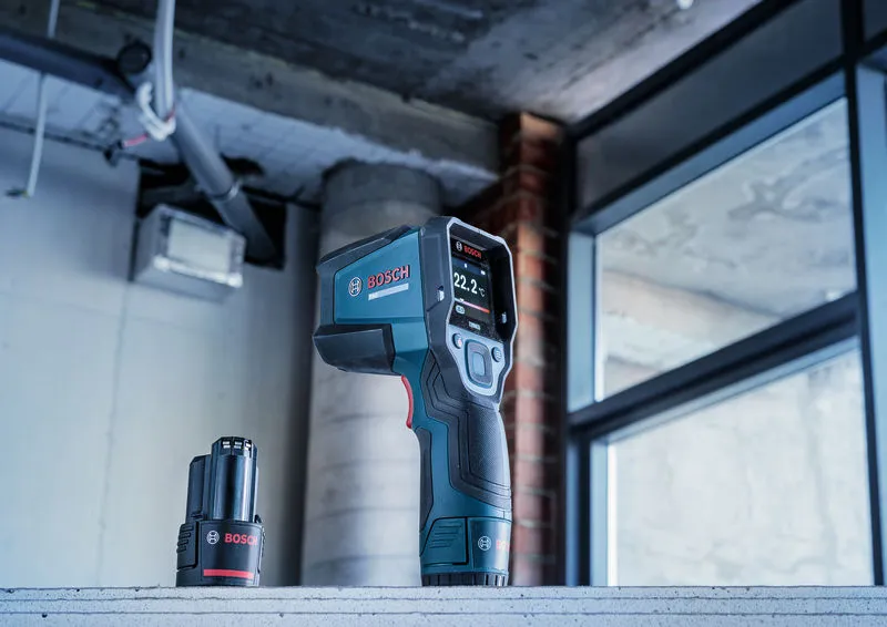 Digital thermo detector and battery placed on a concrete surface in a construction area.