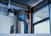 Digital thermo detector and battery placed on a concrete surface in a construction area.