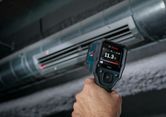 Person using a thermo detector to measure air temperature at an HVAC vent.