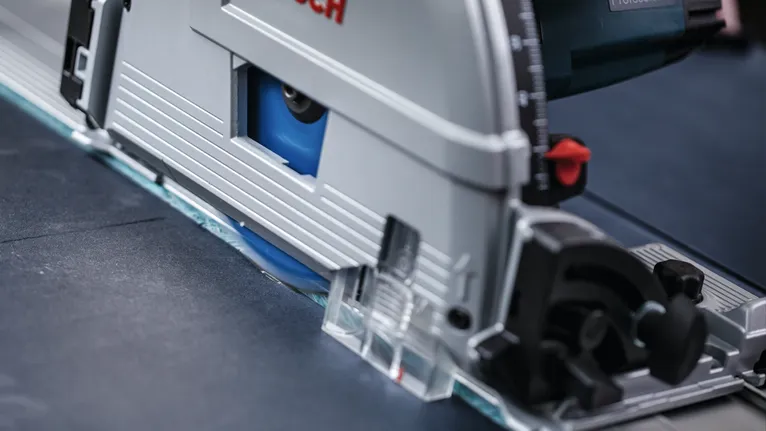 Circular saw making a precise cut through a dark sheet material.