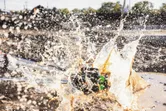 Laser leveling tool falls in muddy water, creating a large splash.