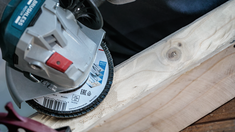 Angle grinder cutting a wooden plank.