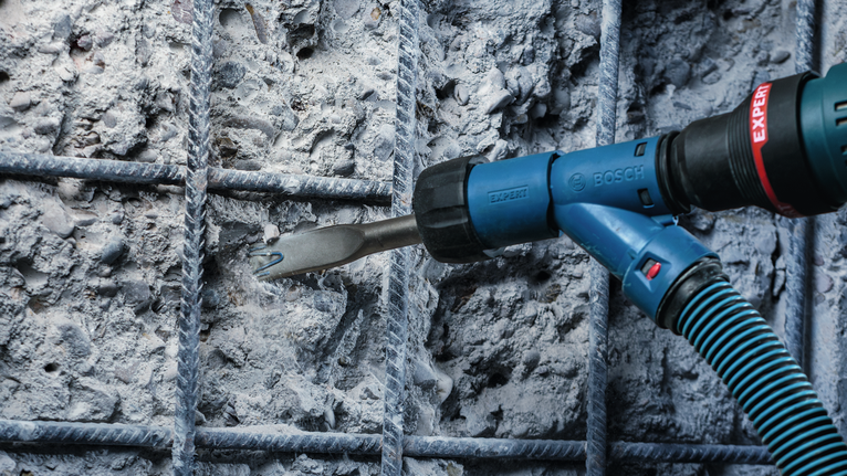 Rotary hammer chisel removing concrete between reinforced steel bars.