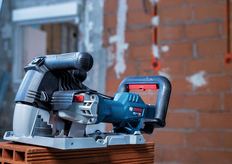 Wall chaser power tool placed on a brick in a construction area.