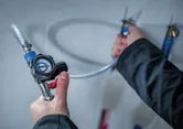 A person adjusts a pressure regulator attached to a flexible hose.