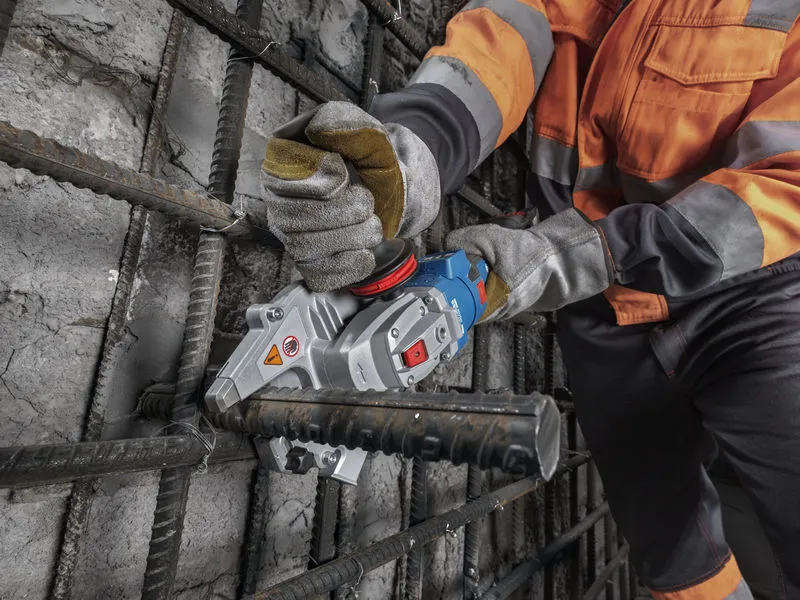 A person wearing safety equipment cuts rebar with a cordless rebar cutter.
