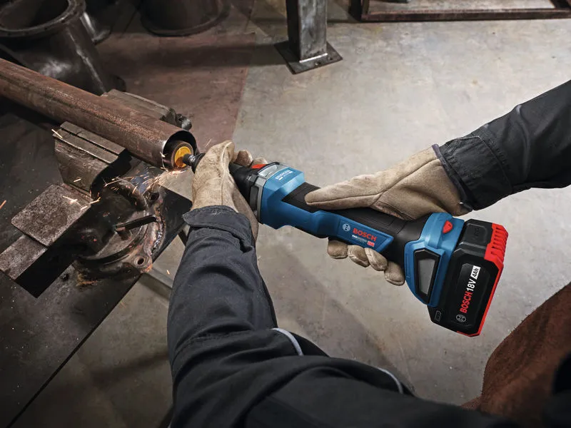 A person wearing safety equipment uses a cordless straight grinder to smooth a metal pipe.