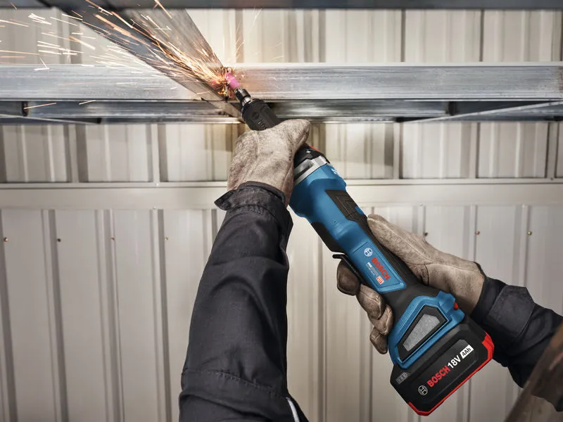 A person wearing safety equipment grinds a metal beam with a cordless straight grinder.