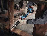 A person wearing safety equipment grinds a metal beam with a cordless straight grinder.