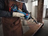 A person wearing safety equipment grinds a metal beam with a cordless straight grinder.