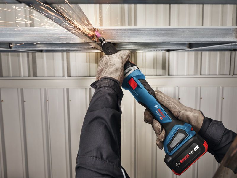 A person wearing safety equipment grinds a metal beam with a cordless straight grinder.