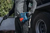 A person wearing safety equipment refuels a truck using a portable pump.