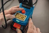 Person adjusts temperature on a cordless soldering iron with a brass cleaning pad.