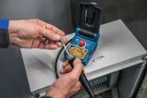 A person replaces the tip on a cordless soldering iron at a workstation.