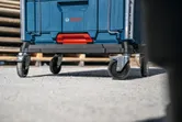 Wheeled cart with a blue storage box sits on a concrete surface.