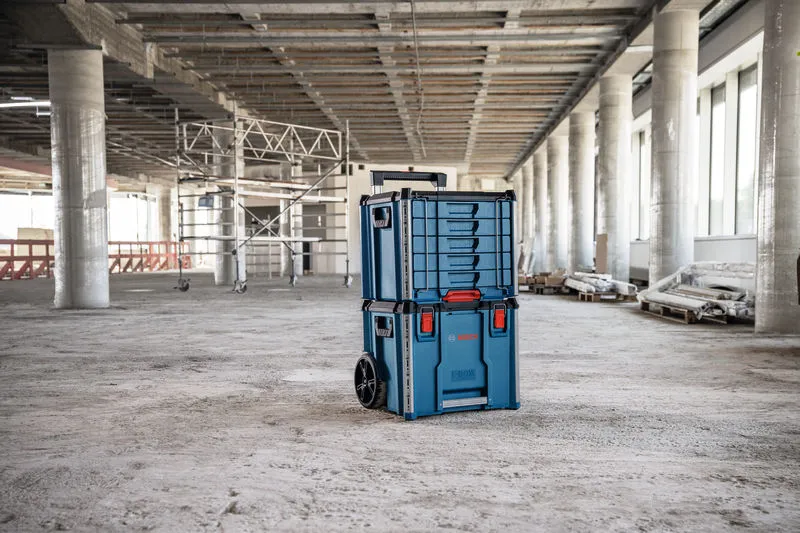 Rolling carrying case system with drawers stands in the middle of a construction site.