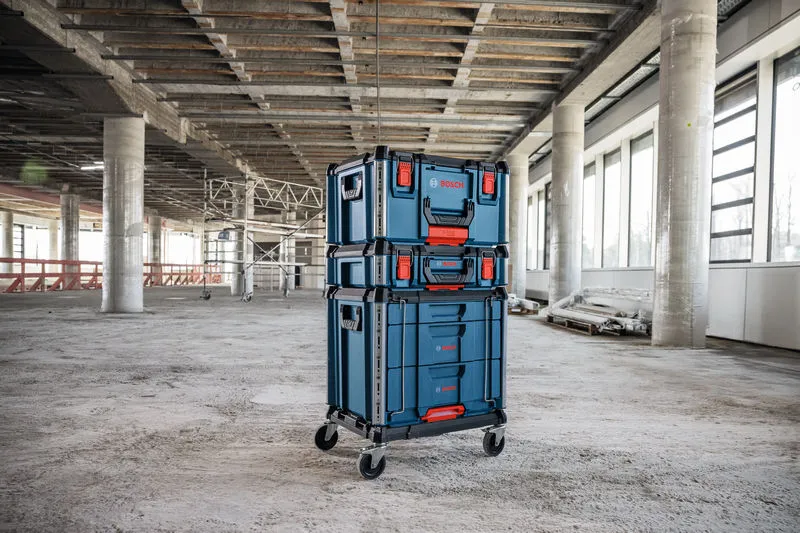 Stacked wheeled contractor cart with cases stands in a large unfinished building.
