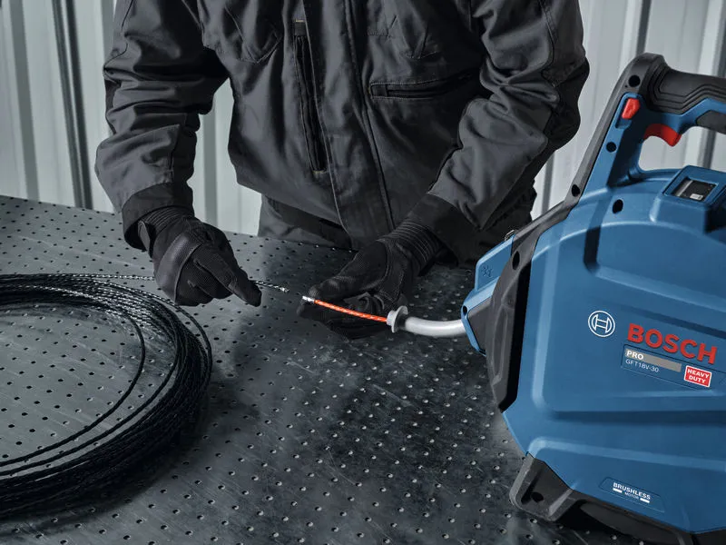 A person wearing safety equipment feeds wire into a cable pulling machine.