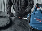 A person wearing safety equipment feeds wire into a cable pulling machine.
