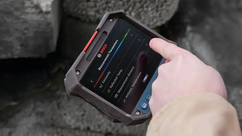 Person using a thermo camera to adjust measurement parameters outdoors.