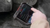 Person using a thermo camera to adjust measurement parameters outdoors.