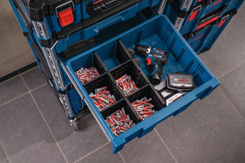 Carrying case drawer with organized compartments, a cordless drill and assorted wall plugs.