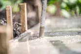Concrete vibrator smoothing freshly poured concrete in a wooden frame.