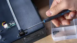 Person uses a screwdriver to assemble electronic equipment.