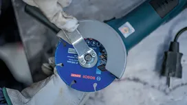 Person wearing safety equipment tightens the blade on an angle grinder.