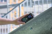 A person uses a laser measure on a metal beam.