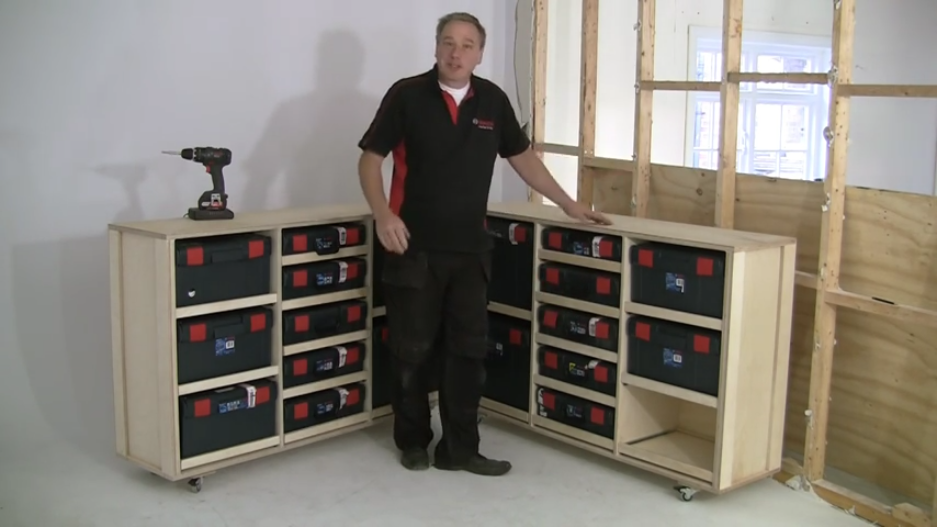 A man stands beside a wooden tool cabinet with Bosch Professional tool boxes.