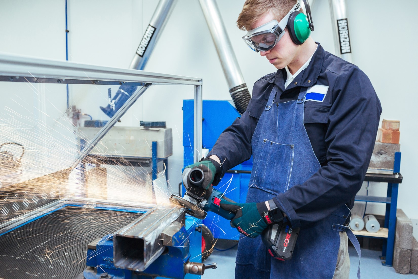 A worker in safety gear operates a Bosch tool, creating sparks while cutting metal.