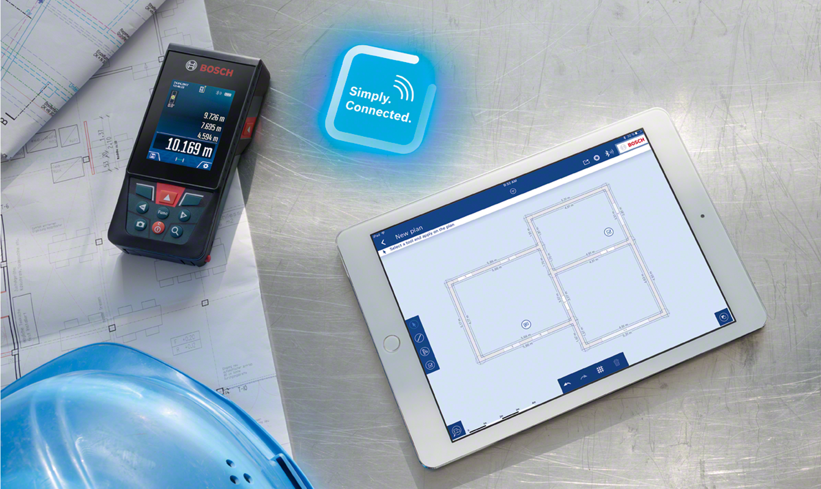 A Bosch laser measure and tablet showing construction plans on a metallic surface.