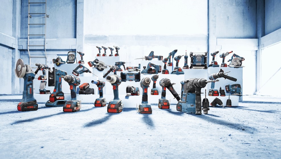A variety of Bosch Professional power tools arranged on a light floor in a spacious, bright setting.