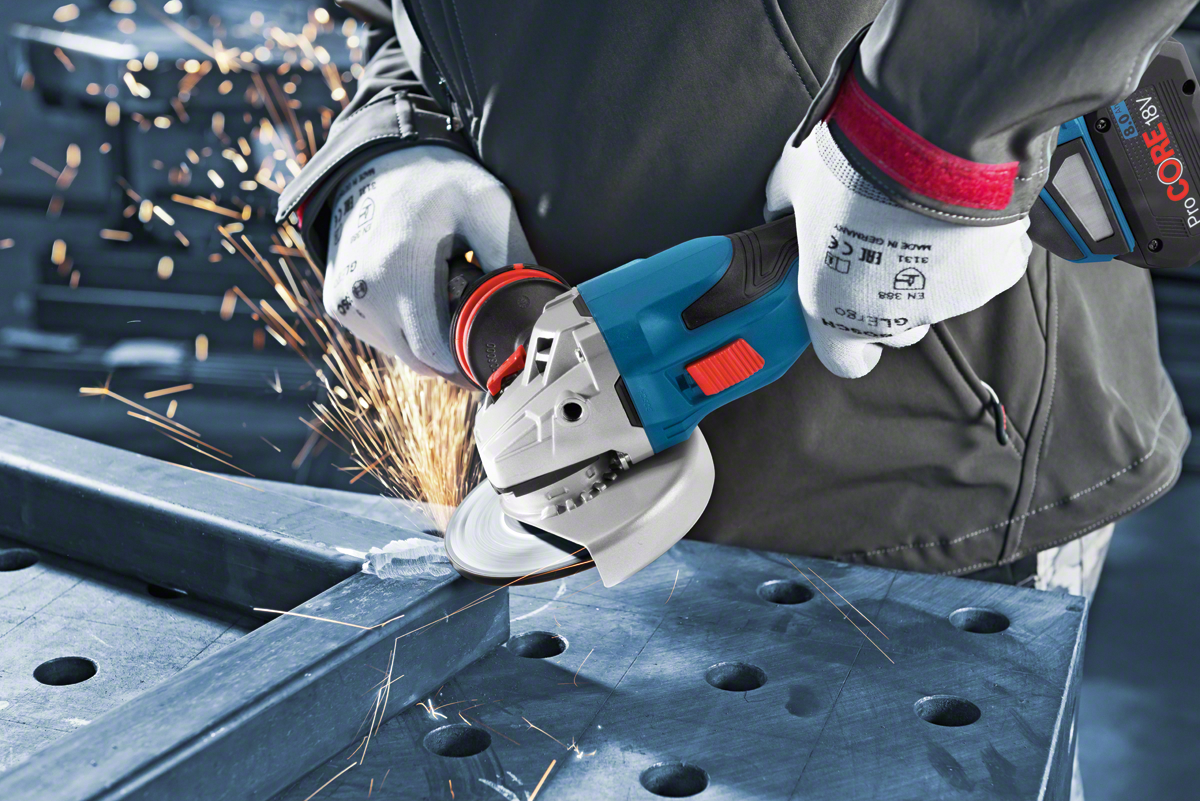 A Bosch Professional angle grinder cuts metal, sparks flying, on a workbench.