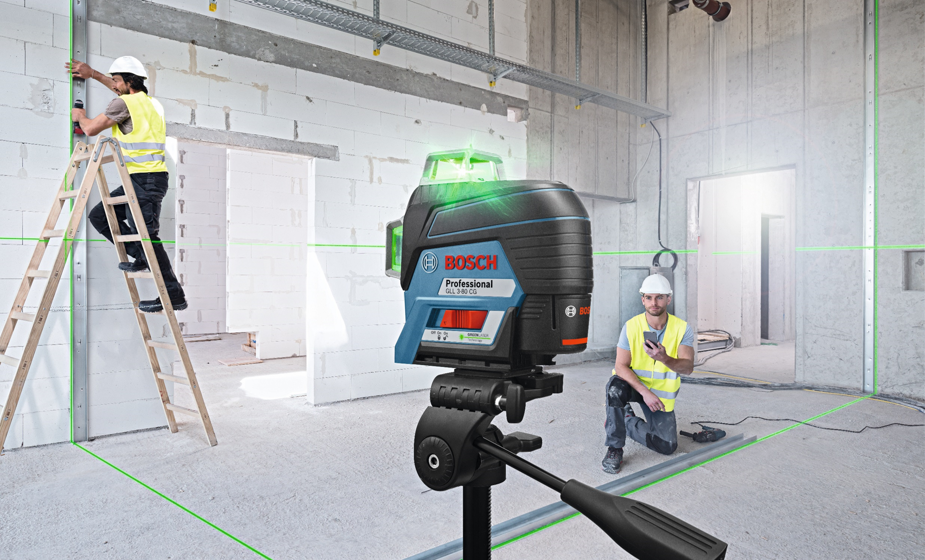 Bosch Professional laser level on a tripod with two workers in safety vests on a construction site.